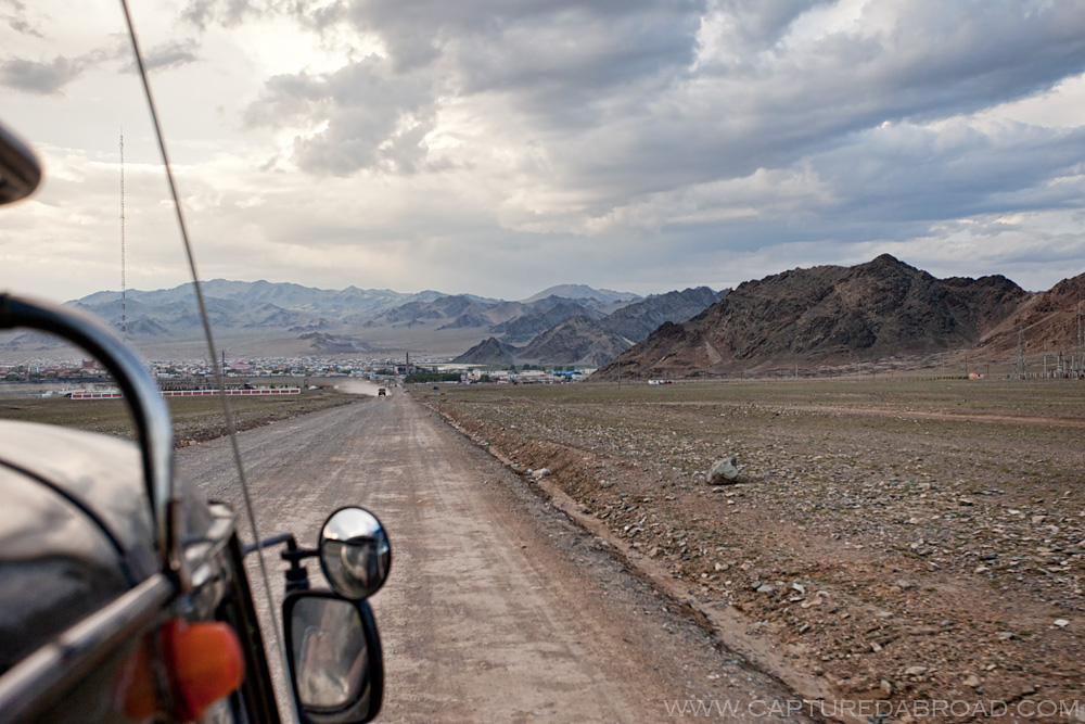 russian jeep arrives on dirt rd at sunset in Olgii Mongolia