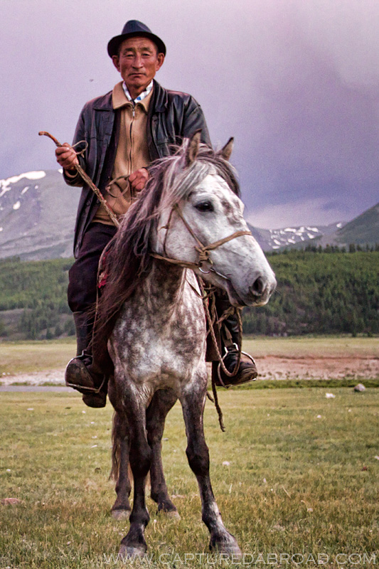 Man on a silver horse with a purple sunset in Mongolia Khurgan nuur