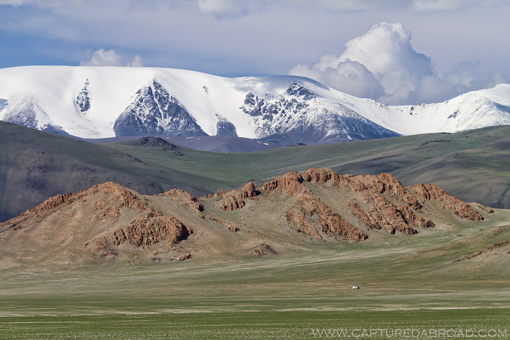 Bayan-Ölgii Province, snow capped mountains and fields of grass